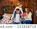 Happy family in white sweaters exchanging a Christmas gift in a cozy loft-style room with a brick 131838718