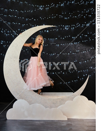 A beautiful blonde woman in a black top and a voluminous pink tulle skirt poses in a large glitter A beautiful blonde woman in a black top and a voluminous pink tulle skirt poses in a large glitter 131838722