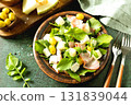 Fresh arugula salad with prosciutto, melon, and olives for a delicious summer meal. 131839044