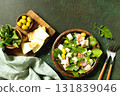 Fresh arugula salad with prosciutto, melon, and olives for a delicious summer meal. Top view flat lay background. Copy space. 131839046