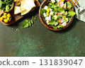 Fresh arugula salad with prosciutto, melon, and olives for a delicious summer meal. Top view flat lay background. Copy space. 131839047
