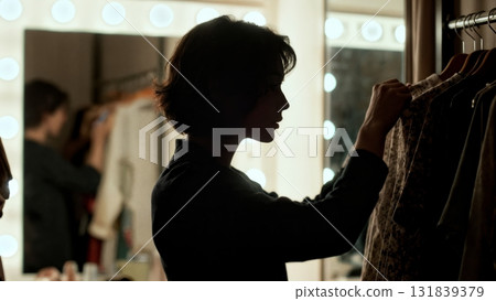 A person browsing a rack of clothes. Retail, fashion, clothes, selection, personal 131839379