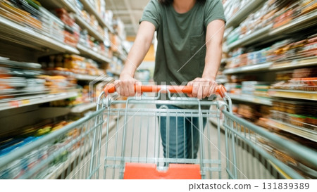 A person pushing a shopping cart down an aisle. Grocery shopping, supermarket, food, daily life, consumerism 131839389