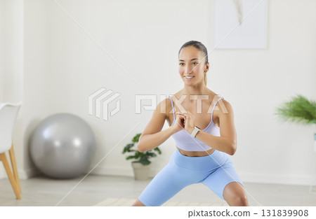 Positive Woman Doing Squats During Home Fitness Training 131839908