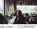 In a warm coworking space filled with plants, a man sits at a table, focusing on his work. Bright colors from decor and light fill the inspiring atmosphere 131840467
