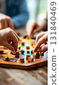 Participants immerse themselves in a strategic board game, placing wooden houses on the game board while surrounded by friends in a warm and inviting atmosphere 131840469