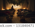 In a tranquil room filled with greenery, participants lie on mats while a facilitator leads a sound therapy session using singing bowls and candles for ambiance 131840471