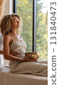 A person experiences sound therapy with a brass bowl in a peaceful environment, promoting relaxation and mindfulness. The tranquil indoor setting enhances the calming experience 131840473
