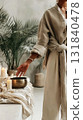 In a tranquil atmosphere filled with greenery, a person interacts with a Tibetan singing bowl, creating soothing sound vibrations while surrounded by softly glowing candles 131840478