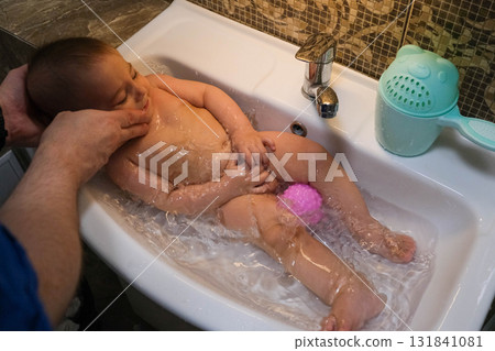 Baby Bathing in Sink with Pink Ball Baby Bathing in Sink with Pink Ball 131841081
