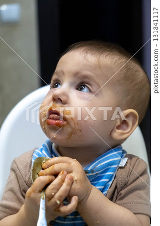 Baby with Food on Face Holding Spoon Baby with Food on Face Holding Spoon 131841117