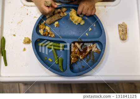 Child Eating Messy Meal on High Chair 131841125