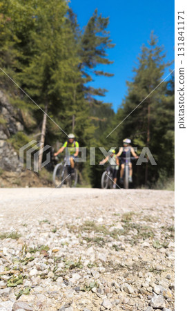 Cyclists riding mountain bikes on gravel road in forest Cyclists riding mountain bikes on gravel road in forest 131841171