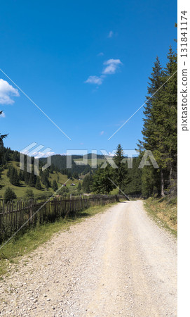 Gravel road winding through scenic mountain valley in Romania Gravel road winding through scenic mountain valley in Romania 131841174