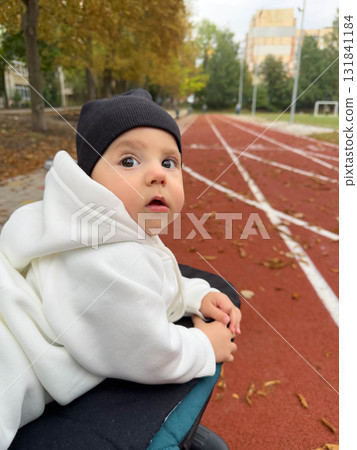 Baby in Hoodie on Track Field in Autumn 131841184