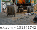 Construction site in which an excavator with lowered bucket to the surface of street tiles. Specialized machines for excavation, laying and replacement of pipes, underground utilities. Working place 131841742