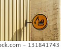 A circular orange warning sign depicting an excavator mounted on a metal construction site fence. This sign warns of a potential hazard to life and health. Safety precautions at the work site 131841743
