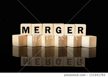 Wooden blocks spell out MERGER against a black background, creating a reflection below. It represents business strategy, success, and joining forces 131841763