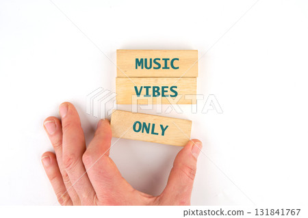 A hand places a wooden block, with the word only on it, beneath two other blocks. The upper blocks say music vibes. The setup is on a white Surface A hand places a wooden block, with the word only on it, beneath two other blocks. The upper blocks say music vibes. The setup is on a white Surface 131841767