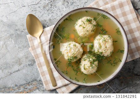 Matzoh Ball Soup soup in a rich chicken broth with the addition of carrot, dill and celery closeup on the plate. Horizontal top view 131842291