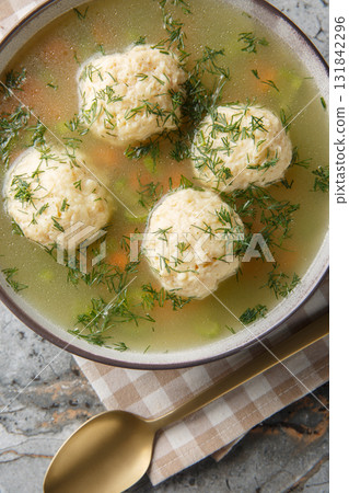 Delicious Matzo ball soup, Jewish traditional cuisine closeup on the plate. Vertical top view Delicious Matzo ball soup, Jewish traditional cuisine closeup on the plate. Vertical top view 131842296