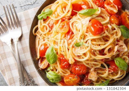 Margherita Spaghetti with cherry tomatoes, olive oil, butter, garlic, fresh basil, creamy mozzarella tossed closeup on the plate. horizontal top view 131842304