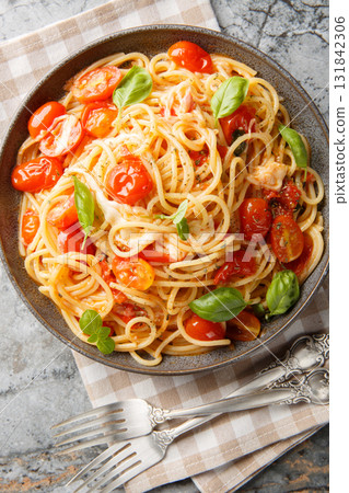 Margherita Spaghetti made with tomatoes, basil, and mozzarella closeup on the plate. Vertical top view 131842306