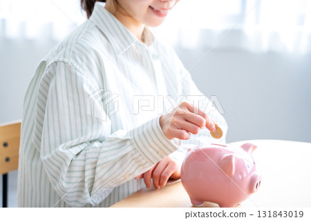 A woman who puts money in a piggy bank A woman who puts money in a piggy bank 131843019