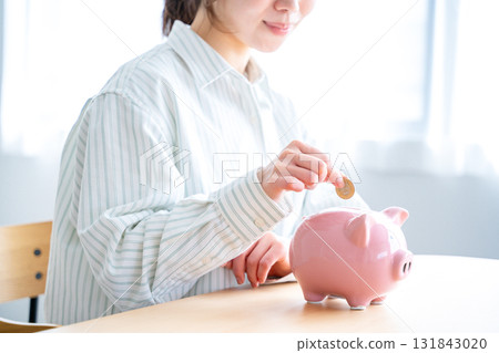 A woman who puts money in a piggy bank A woman who puts money in a piggy bank 131843020