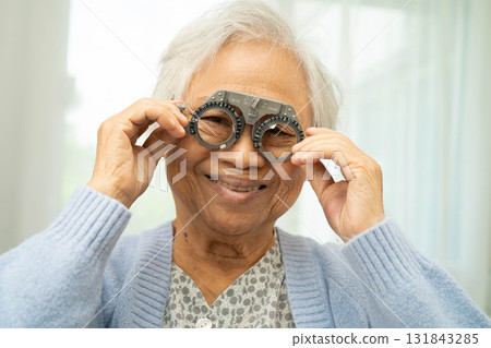Optometrist checking Asian elderly woman ophthalmic vision eye test and using optical trial frame. 131843285