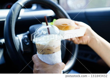 Asian woman driver hold and eat hamburger food in car. 131843432