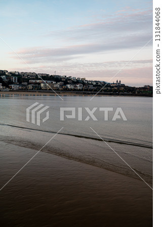 The shallow Concha Beach in the morning glow and the townscape lined with resort hotels in the distance in San Sebastian The shallow Concha Beach in the morning glow and the townscape lined with resort hotels in the distance in San Sebastian 131844068