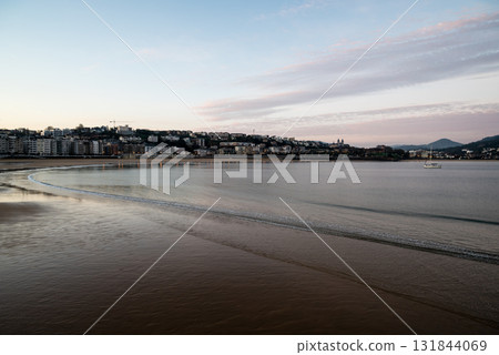 The shallow Concha Beach in the morning glow and the townscape lined with resort hotels in the distance in San Sebastian The shallow Concha Beach in the morning glow and the townscape lined with resort hotels in the distance in San Sebastian 131844069