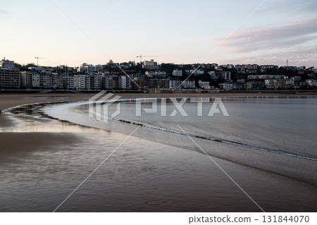 The shallow Concha Beach in the morning glow and the townscape lined with resort hotels in the distance in San Sebastian The shallow Concha Beach in the morning glow and the townscape lined with resort hotels in the distance in San Sebastian 131844070
