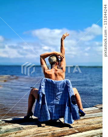 Artistic nude portrait of woman posing on wooden pier by Baikal lake 131844244