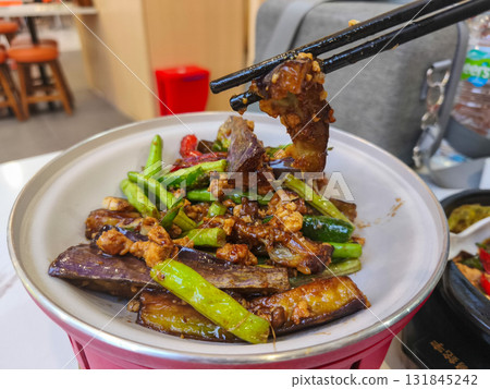 Delicious homemade stir fried eggplant with minced chicken and green beans, a popular Asian dish, served in a white bowl with chopsticks. 131845242