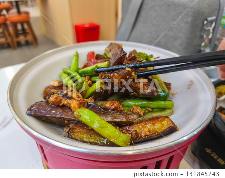 Delicious homemade stir fried eggplant with minced chicken and green beans, a popular Asian dish, served in a white bowl with chopsticks. 131845243