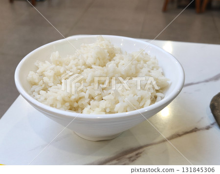 White rice in a bowl on a marble table at a food court with a blurred background. 131845306