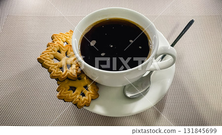A cozy coffee break with black coffee and golden, patterned butter cookies on a textured surface A cozy coffee break with black coffee and golden, patterned butter cookies on a textured surface 131845699