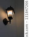 Black Lantern Casts a Warm Glow on a Quiet Evening Wall 131847266