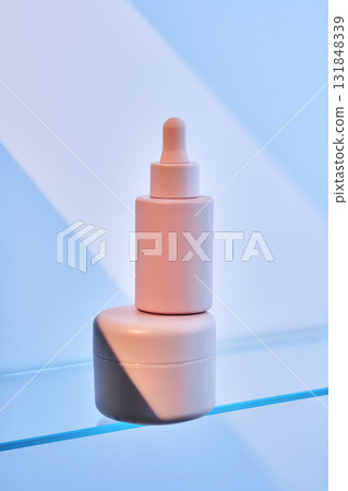 A bottle of serum and cream on the glass shelf of the bathroom. 131848339