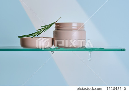 A jar of rosemary cream on the glass shelf of the bathroom. 131848340