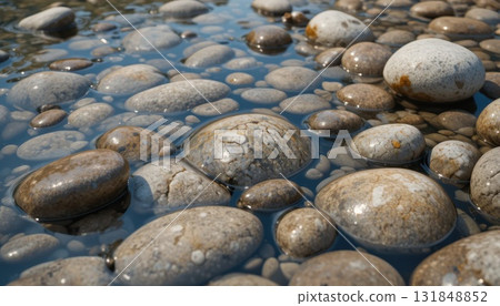 Beautiful Collection of Smooth Stones Submerged in Clear Water Under Bright Sunlight 131848852
