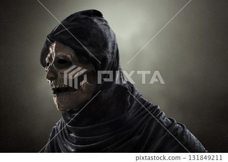 Creepy figure in hooded cloak over dark misty background at night 131849211