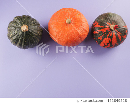 Three colorful pumpkins on purple background Three colorful pumpkins on purple background 131849228