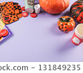 Halloween purple frame background flatlay with pumpkins and party decor 131849235