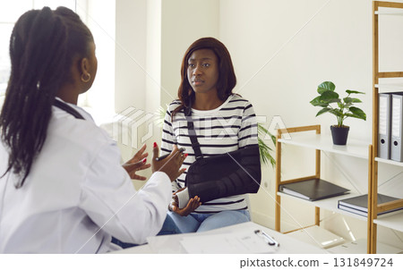 Young African American woman talking to doctor about treatment of her injured arm 131849724