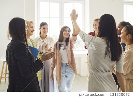 Happy multiracial female team in office applauding and giving high fives while celebrating success. 131850072
