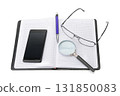 Open Graph Paper Notebook with Smartphone Magnifying Glass Pen and Eyeglasses Arranged on Desk Representing Study Workspace and Analytical Tools 131850083