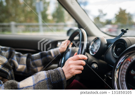 Closeup of woman hands holding steering wheel driving car, drives through the countryside. Closeup of woman hands holding steering wheel driving car, drives through the countryside. 131850105